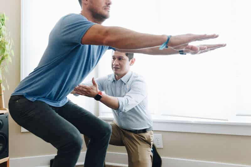 Man learning how to squat with his physical therapist after hip pain