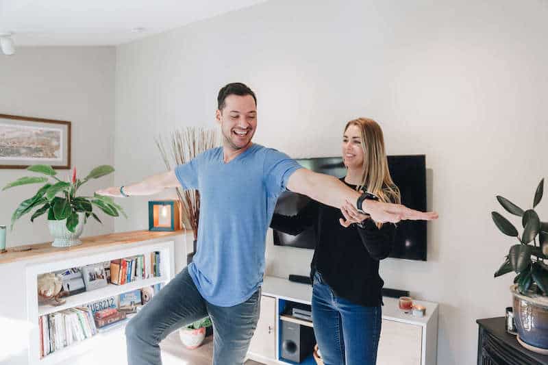 Man working on his balance with his physical therapist in his home