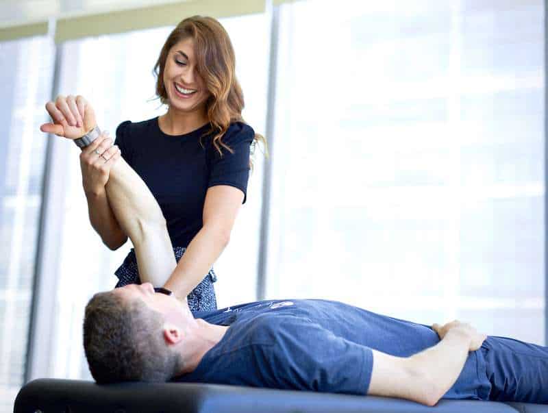 Woman performing hands on treatment, manual therapy, to a man's shoulder