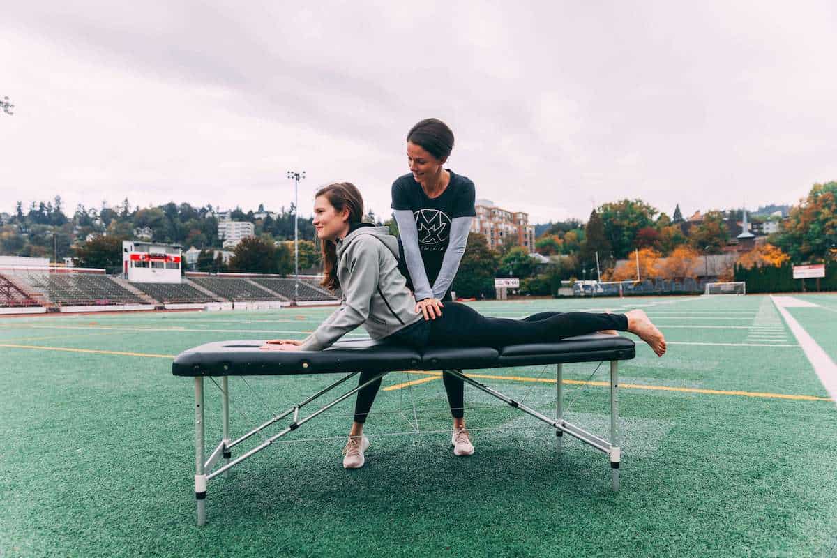 Physical therapist treating woman with low back pain on track and field in Portland, Oregon.