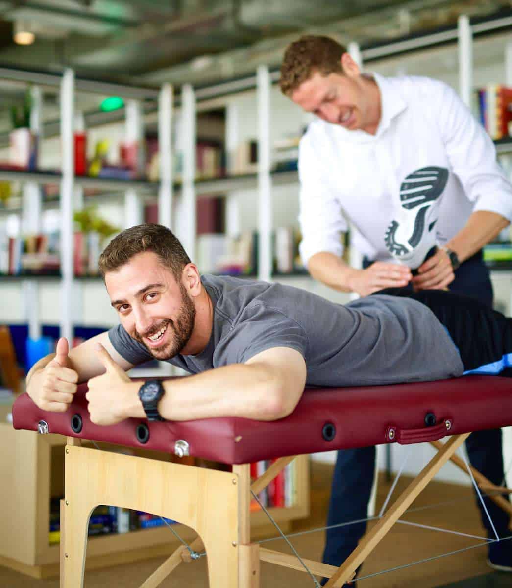 Physical therapist stretching man's quads in his workplace