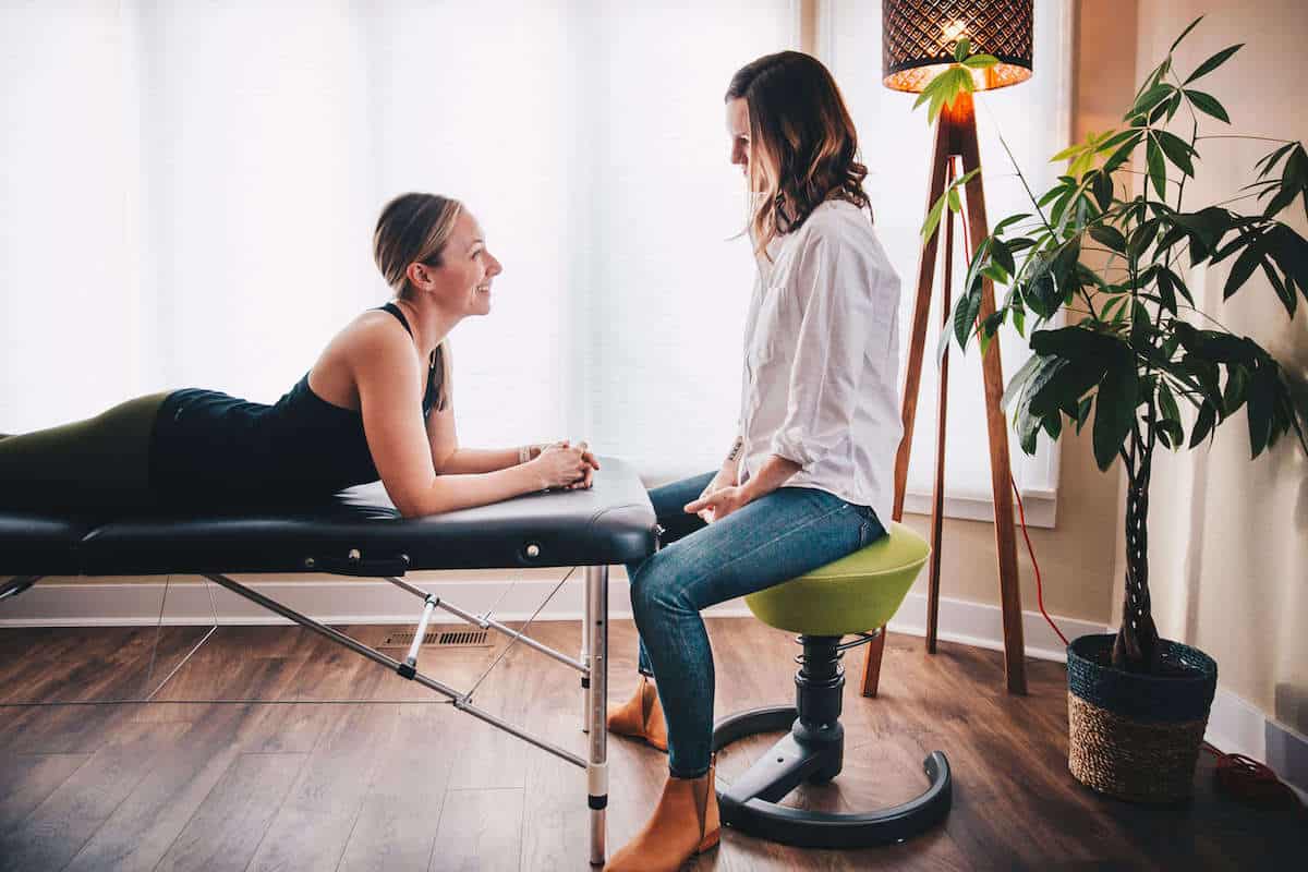 Physical therapist talking to her patient with low back pain in her home