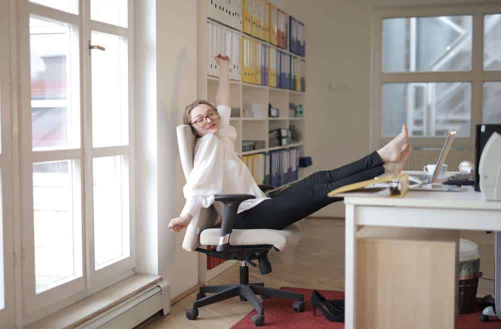 Woman moving and stretching at her desk without her shoes on
