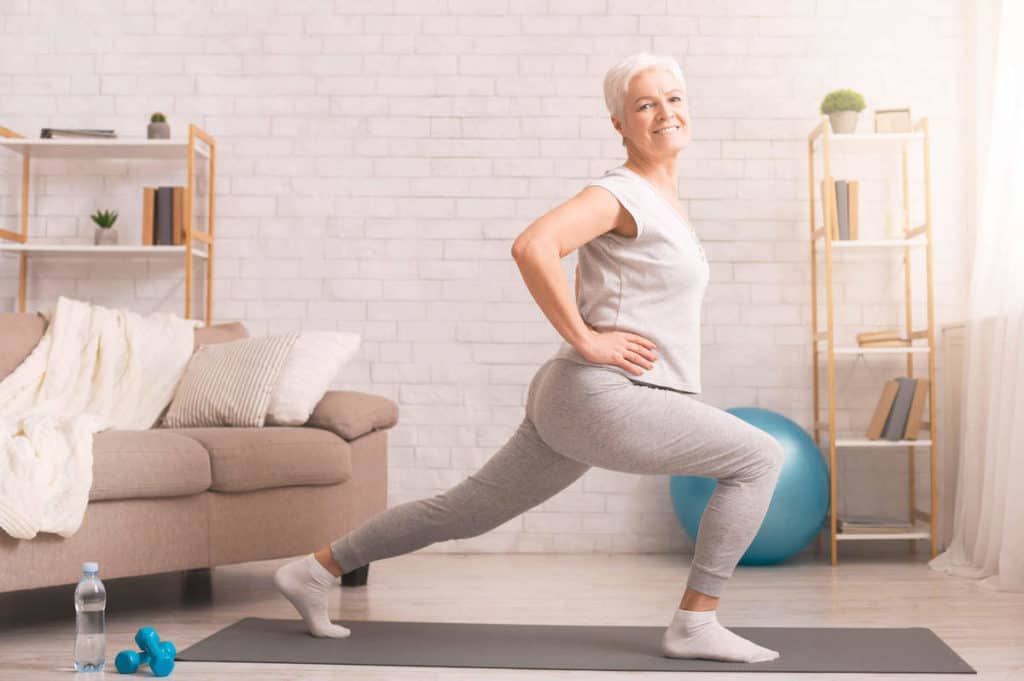 Older woman exercising in a lunge position in home