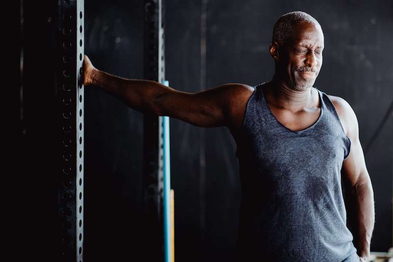 Man stretching his pecs and shoulder with an intense face