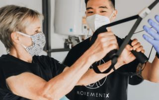 Physical therapist using a mask instructing patient on TRX exercises
