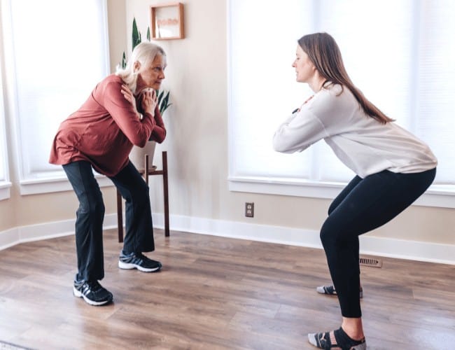 Physical therapist teaching patient how to do a squat in their home