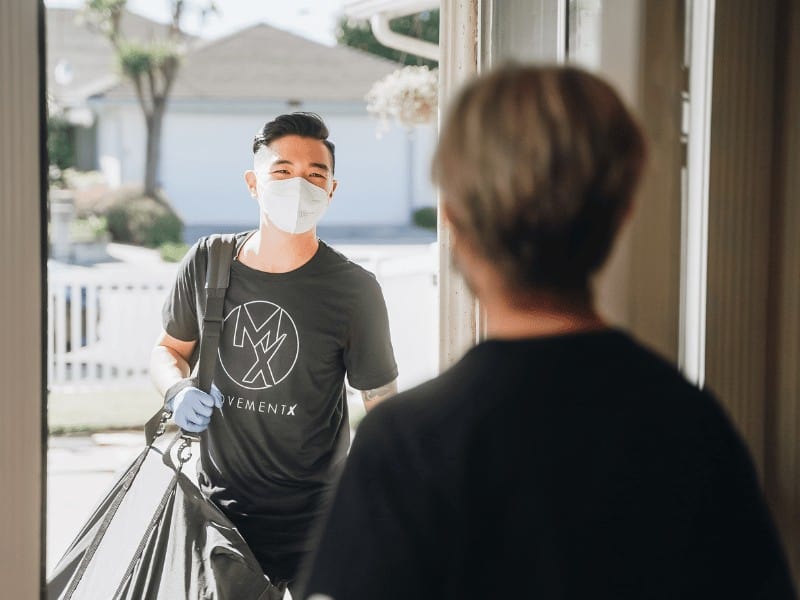 physical therapist arrives at patient's home wearing medical mask and gloves