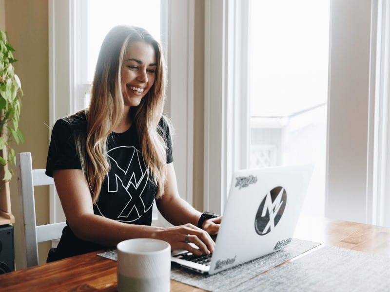 Movement-X member sitting at a table and typing on a laptop