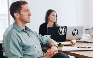 Dr. Scott McAfee, Chief Marketing Officer for Movement X, sitting at a conference table with his team