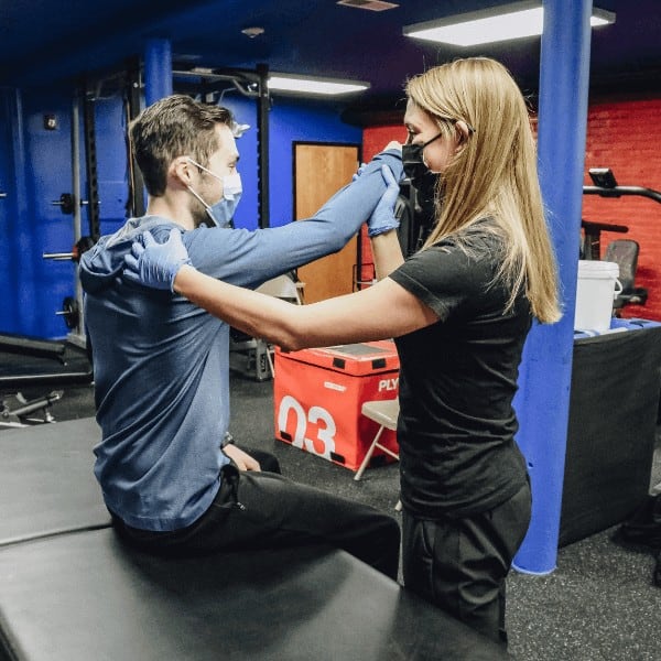 movementx physical therapist working with a patient at our clinic wearing a mask for covid safety