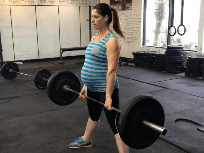 pregnant woman performing a dead lift exercise to strengthen her hips