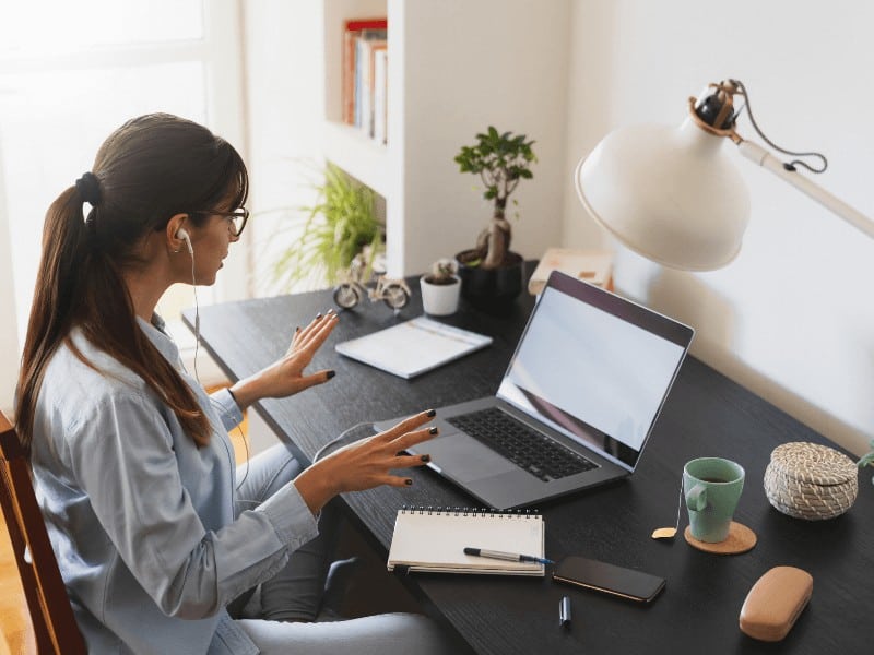 Female busy professional sitting at her desk while working from home with an ergonomic set up for posture optimization