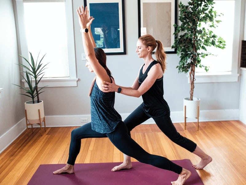 MovementX physical therapist and yoga instructor Sarah Collins helps a patient with hypermobility EDS and HSD perform a yoga pose safely and correctly