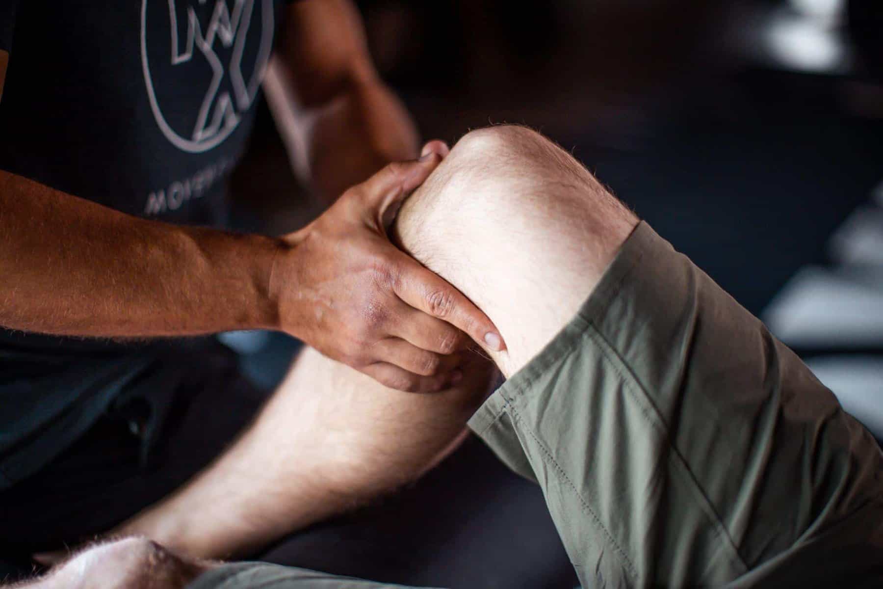 physical therapist performing a hands-on manual therapy technique to improve knee mobility and range of motion on a patient with knee pain