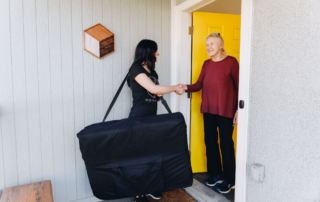 mobile physical therapist with MovementX shaking the hand of an elderly woman at her doorstep before her first physical therapy evaluation appointment