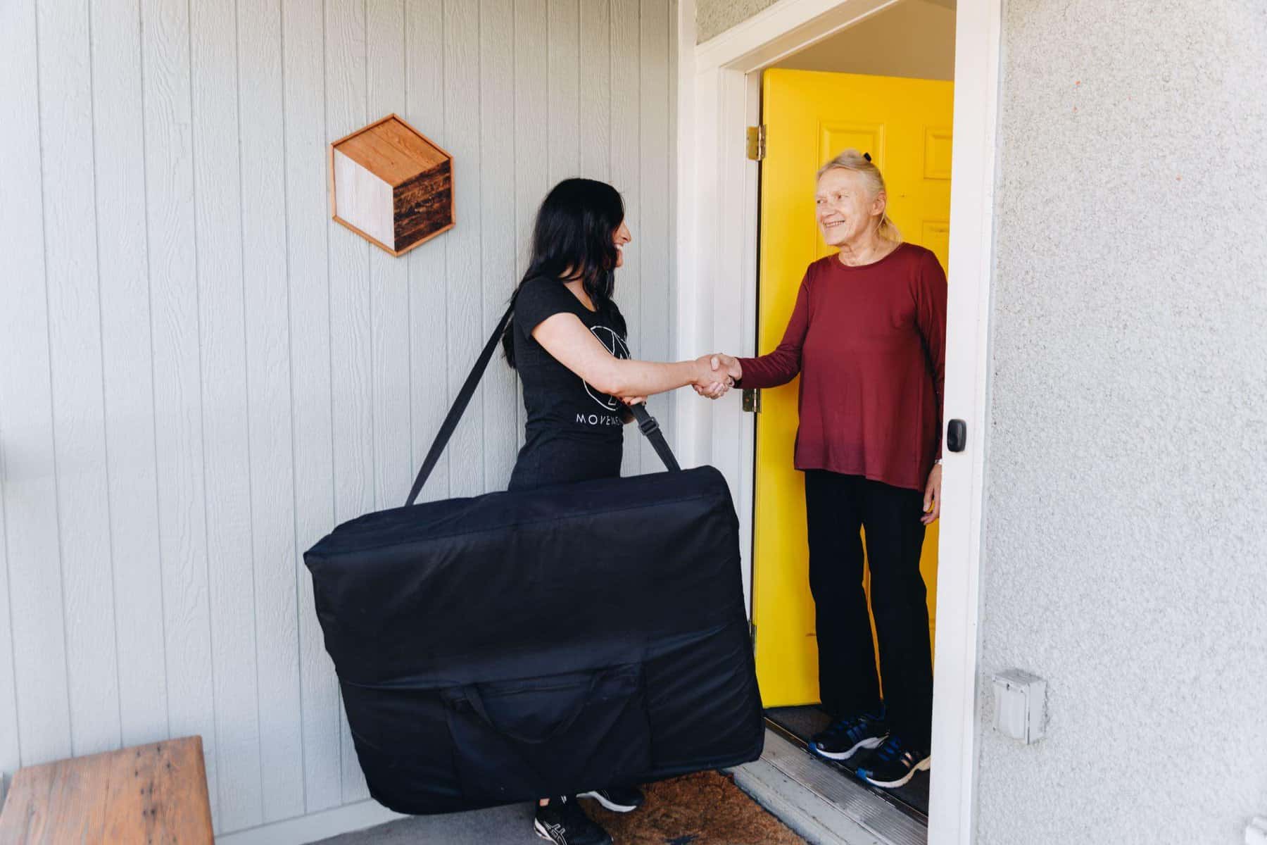 mobile physical therapist with MovementX shaking the hand of an elderly woman at her doorstep before her first physical therapy evaluation appointment