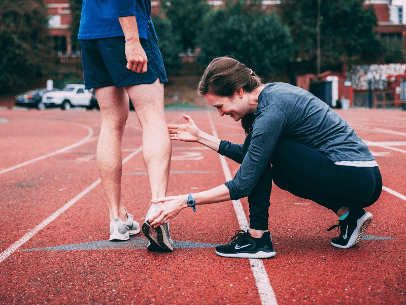 a movementx running physical therapist assessing a runner's running shoes on a track in northern virginia