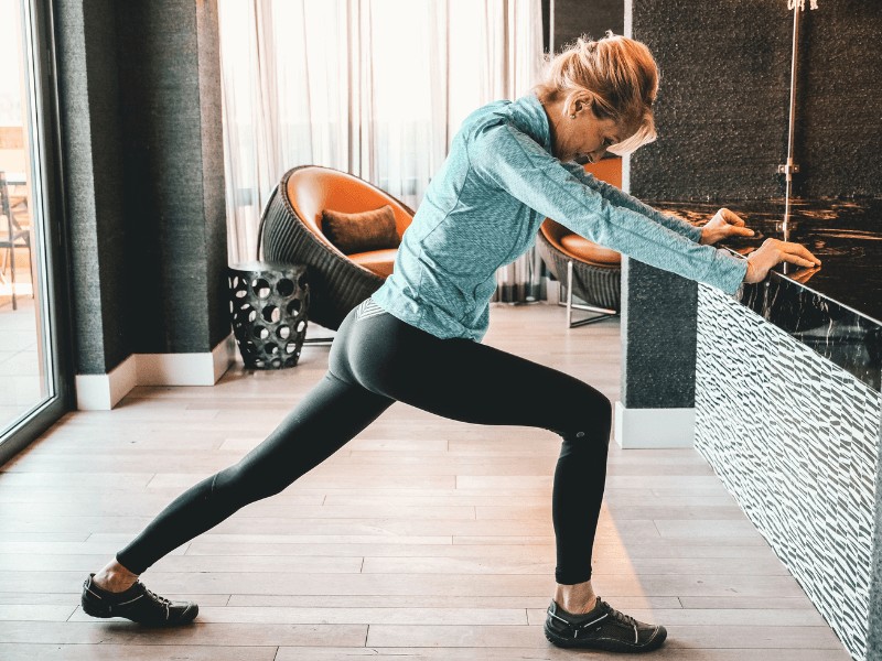 A MovementX physical therapy patient with heel spurs stretching their leg and leaning against a counter.