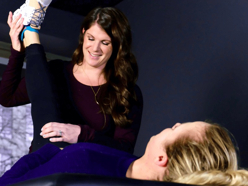 MovementX physical therapist Meg Pezzino helping a patient in Arlington, Virginia stretch their leg while examining their foot.