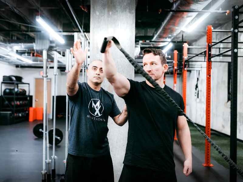 Romin Ghassemi, PT, DPT in North Carolina helping a patient do shoulder rotation tests in a CrossFit gym