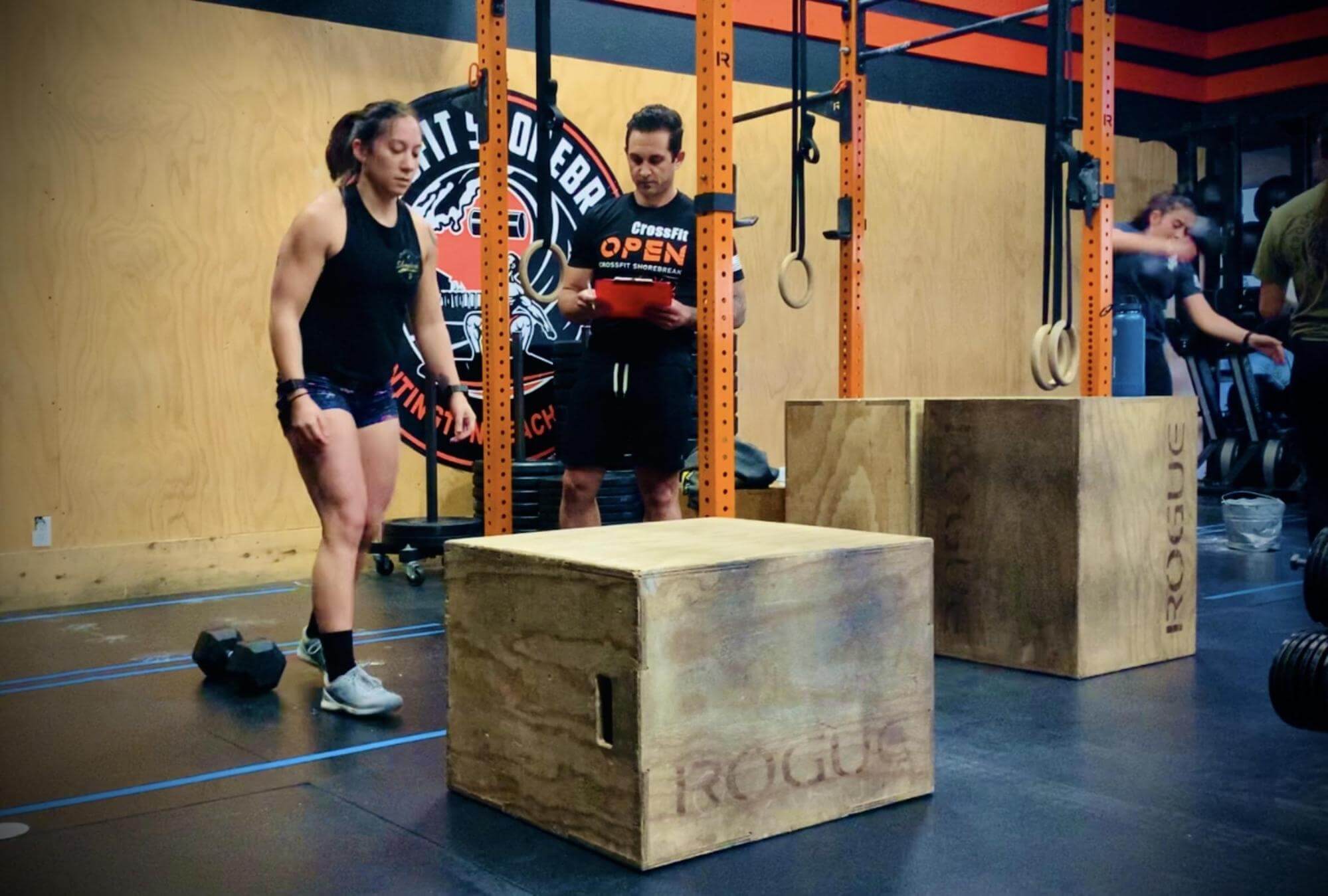 Dr. Jessica Crowder stepping up to a box jump while a CrossFit trainer looks on during a workout in Orange County, CA.