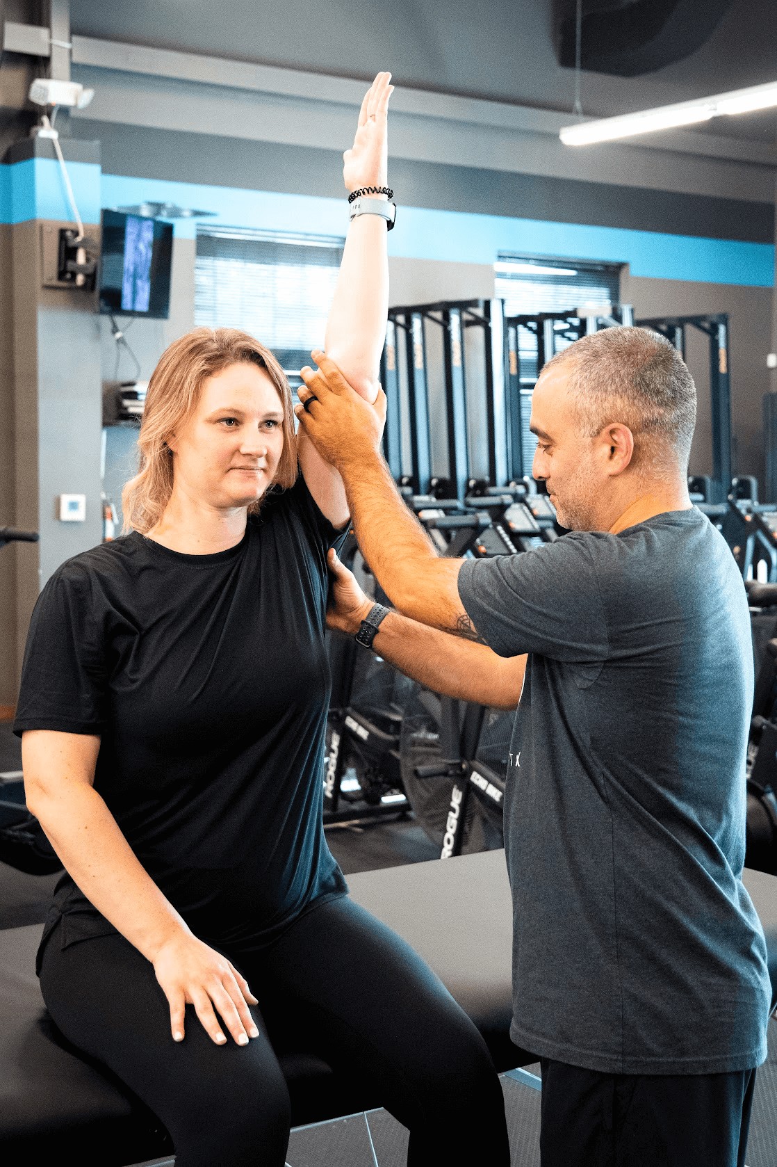 Dr. Romin Ghassemi, PT, DPT helping a patient work through a shoulder impingement by raising her left arm above her head while stabilizing it.