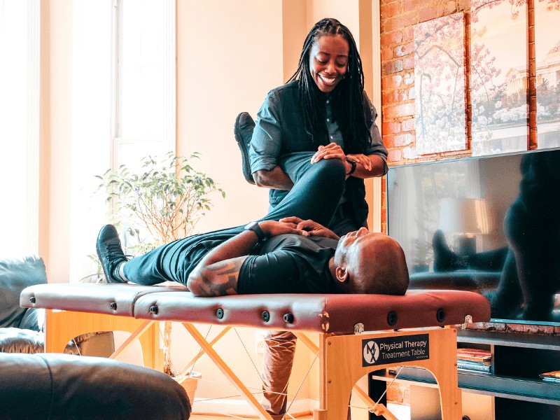 A MovementX provider giving a patient treatment on a treatment table in their living room.