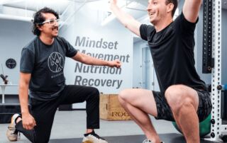 Dr. Rich Ortiz, PT, DPT helping a patient do a full squat in a gym after an ACL operation.