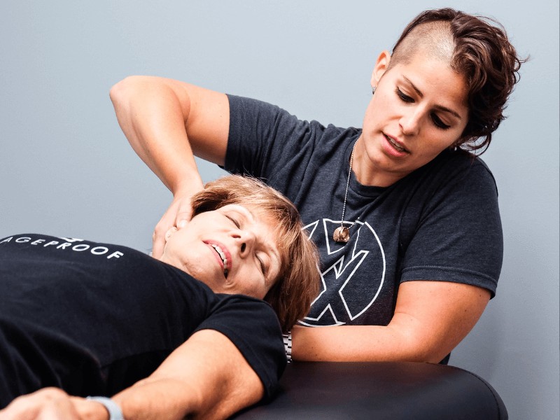 Dr. Emily Harmon, PT, DPT performing neck mobility work on a patient laying on a treatment table.