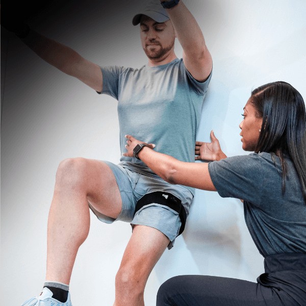 Physical therapist applying blood flow restriction bands to a patient’s leg during strength training.