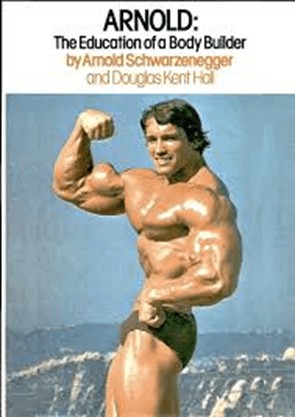 A photo of Arnold Schwarzenegger flexing on a beach in a bathing suit.