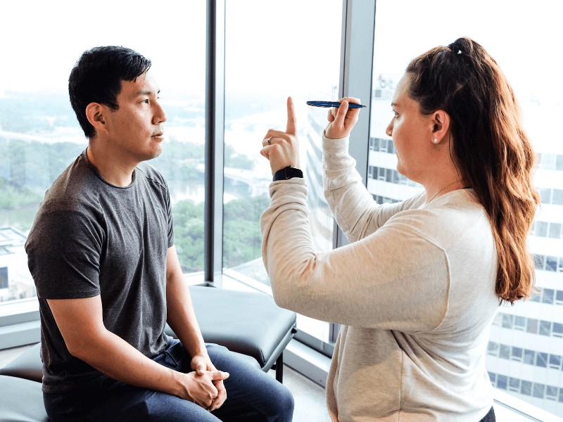 A MovementX provider giving a seated patient an ocular balance examination.