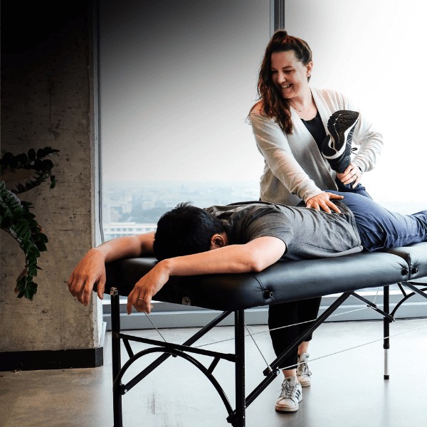 MovementX physical therapist performing a manual therapy treatment for lower back pain for a patient against a light background.