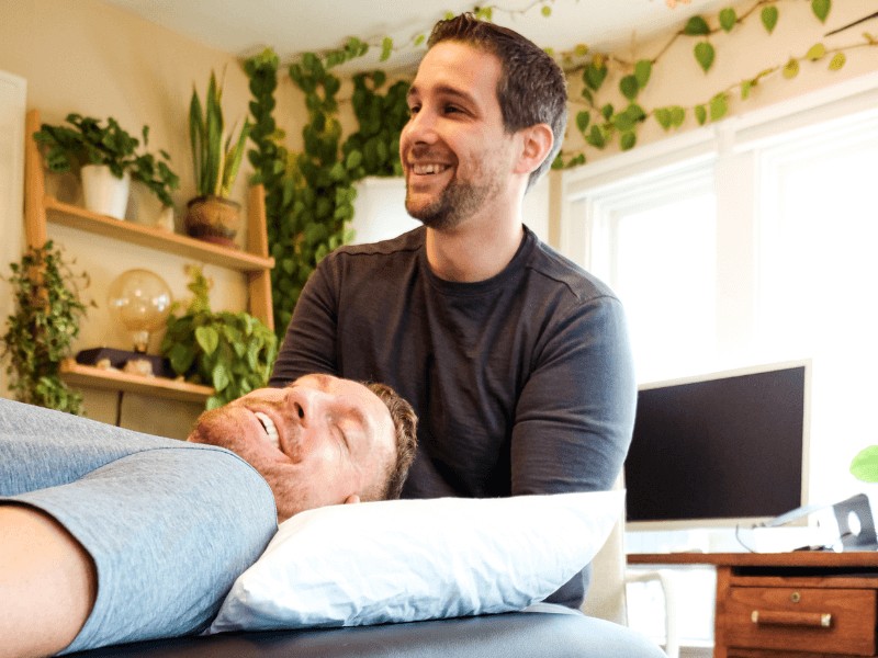 Tony D'Olvidio PT, DPT, helping a patient stretch their neck on a treatment table in the Portland, Oregon area.