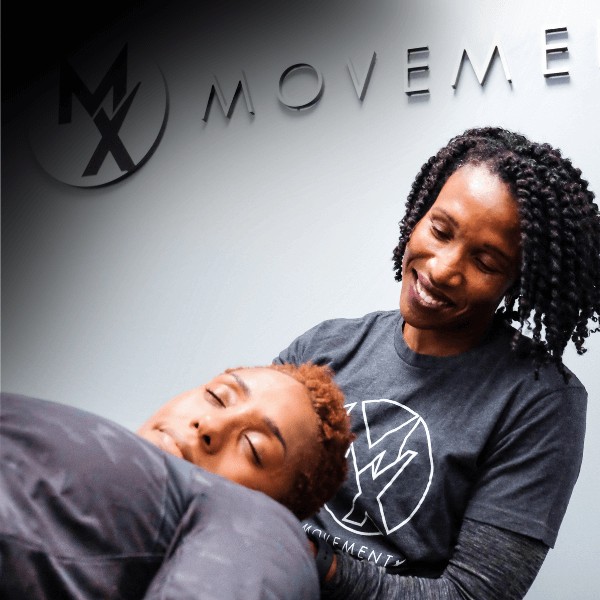A MovementX orthopedic physical therapist using gentle hands-on therapy to release muscle tension and improve neck flexibility through myofascial release techniques in a clinical setting.