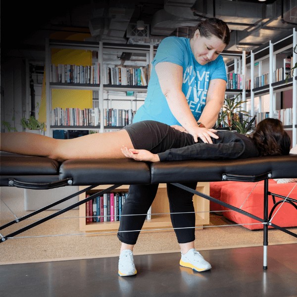 A MovementX orthopedic physical therapist relieving lower back pain and improving spine mobility with hands-on joint manipulation techniques in an office setting.