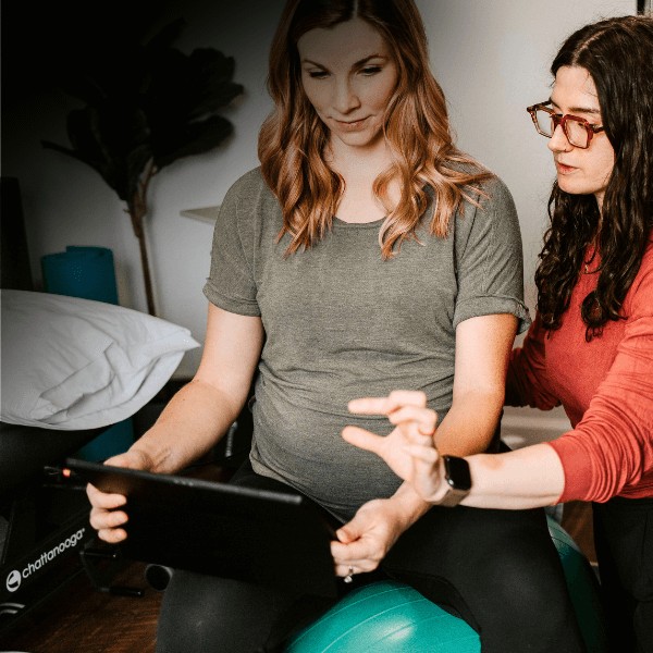 Physical therapist helping a patient with biofeedback training to improve pelvic floor muscle control using real-time feedback.