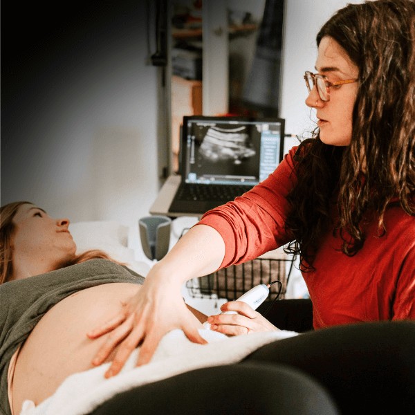 Therapeutic ultrasound being applied on the abdomen of a female patient by a movementx physical therapist for pregnancy.