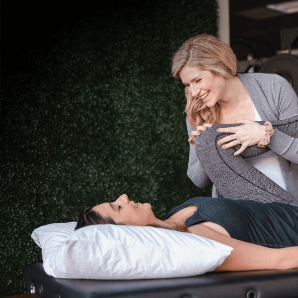 Physical therapist providing manual therapy to relieve pelvic muscle tension through gentle external hands-on techniques in a clinic setting.