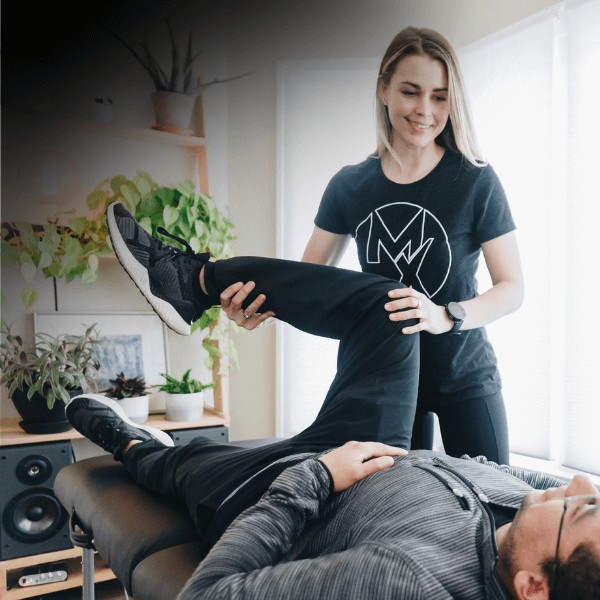 MovementX physical therapist performing a manual therapy treatment for lower back pain for a patient against a light background.