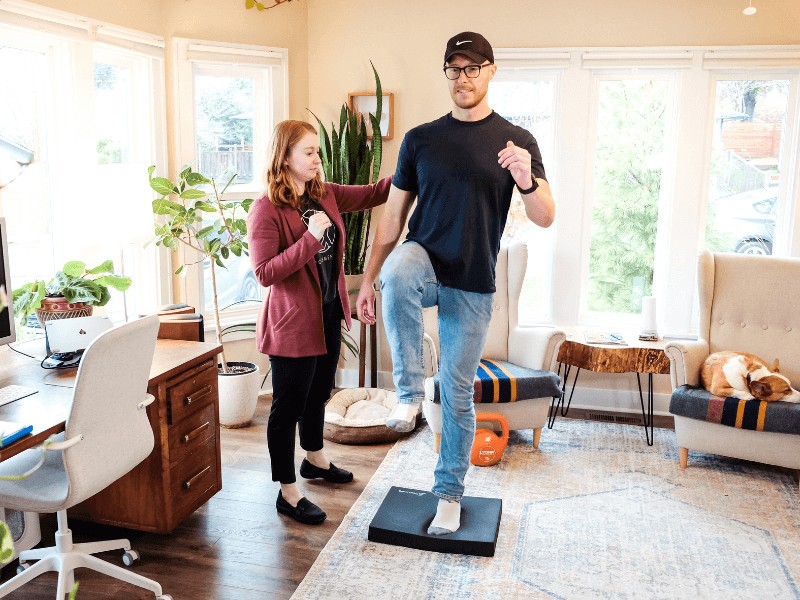 MovementX Neurologic Physical Therapist sydney neumann helping a male patient with balance issues in portland oregon in a home setting