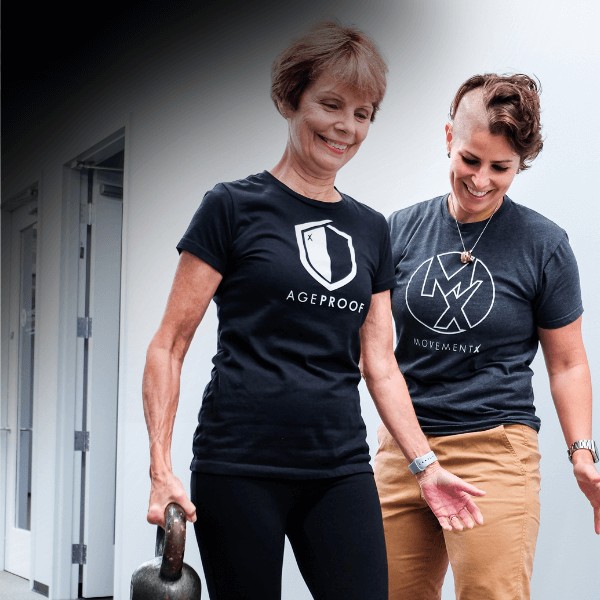 A MovementX vestibular physical therapist supporting a patient with a weight as they practice walking in a clinic setting for improved gait.