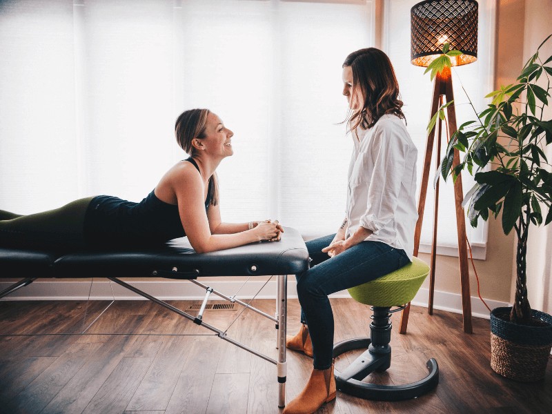 A movementX pelvic health specialist working with a new patient on a treatment table in a home setting.