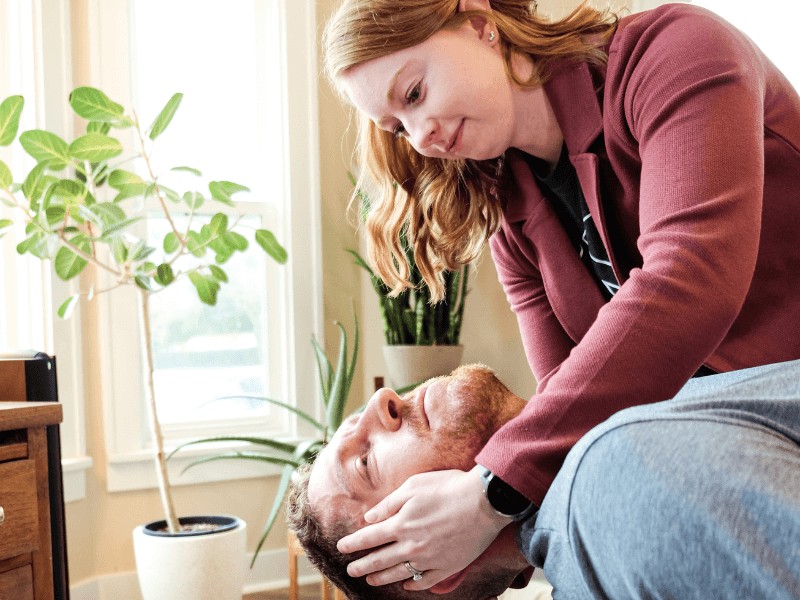 A movementx vestibular physical therapist treating a patient with vertigo using a dix hallpike maneuver in a home setting