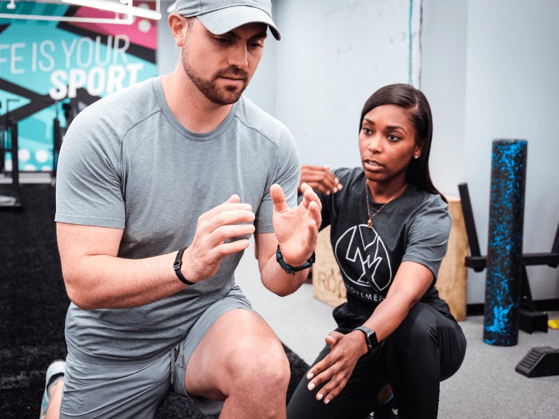 a movementx personal trainer working with a male client on injury prevention in a gym setting