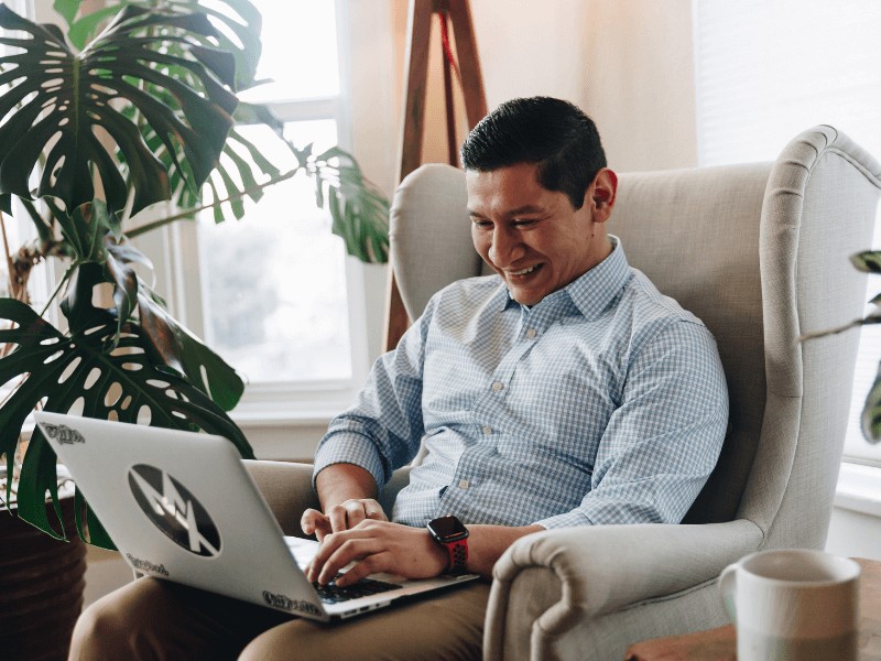 MovementX Provider Jose Reyna, PT, DPT working on his laptop in a chair at home.