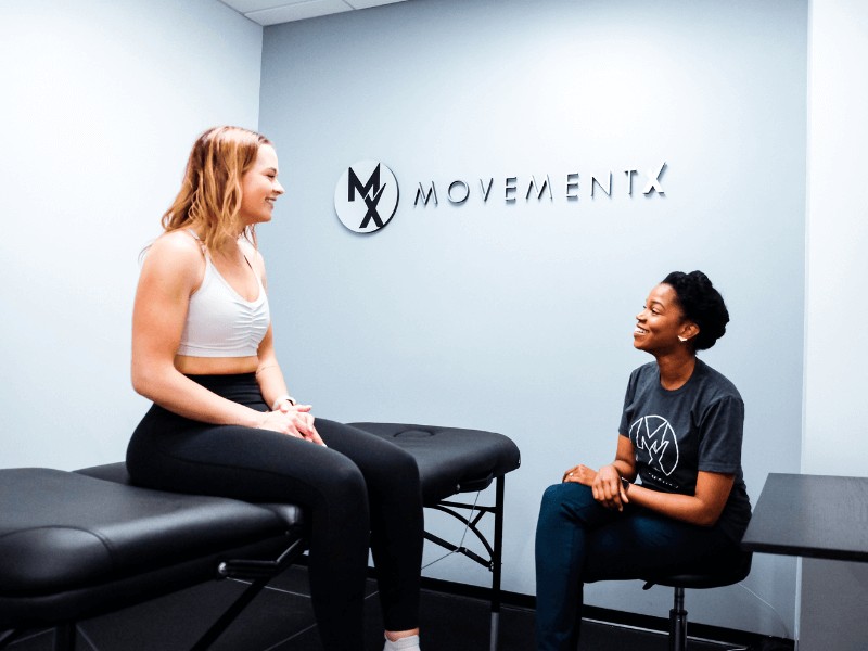 Diana Jean-Mary, PT, DPT consulting with a patient on a treatment table in a MovementX walk-in location.