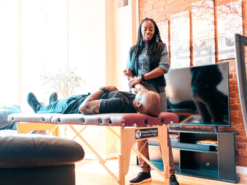 MovementX provider Sabrina Altema, PT, DPT examining a patient on a treatment table in a living room.