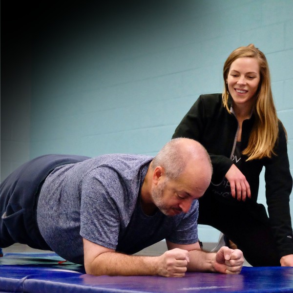 A movementx personal trainer working with a client 1 on 1 in northern virginia doing a plank exercise for core strength